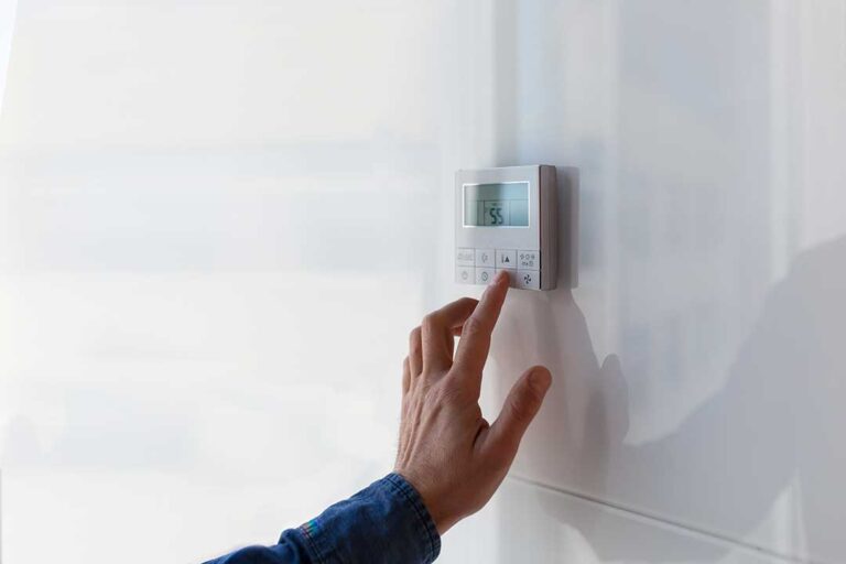 A technician examines the outdoor unit of a residential air conditioning system on a sunny day.